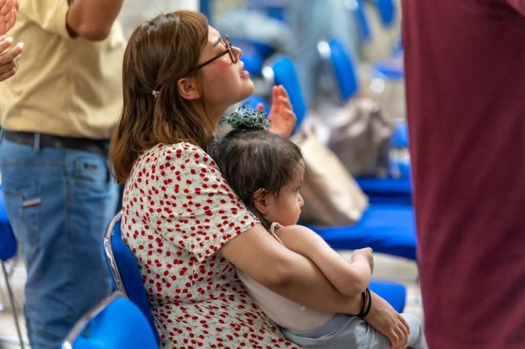 Photo by Israel Torres Mother holding child in a church setting during worship in Mexico City, reflecting spirituality and togetherness.